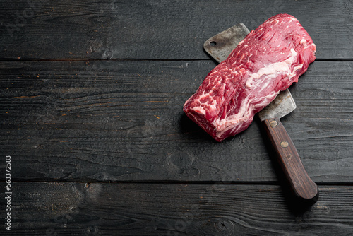 Beef fillet mignon cut raw , with old butcher cleaver knife, on black wooden table background, with copy space for text