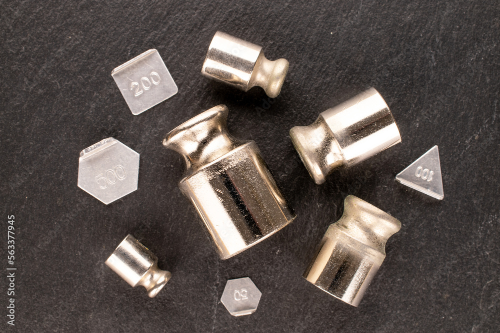 Several metal weights for old jewelry scales on slate stone, macro, top view. Several metal weights for old jewelry scales on slate stone, macro, top view.