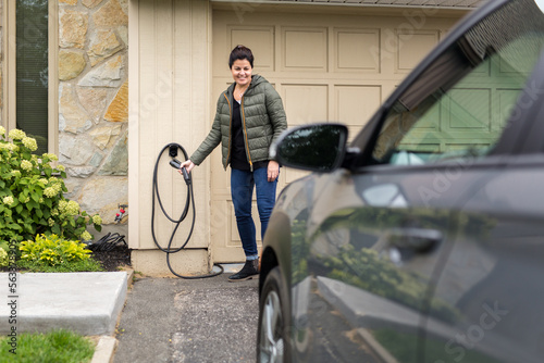 Femme prend le câble de chargement pour sa voiture à propulsion électrique photo