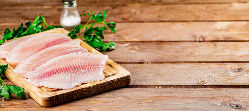 Raw fish fillet with parsley on a cutting board. Raw fish fillet with parsley on a cutting board.