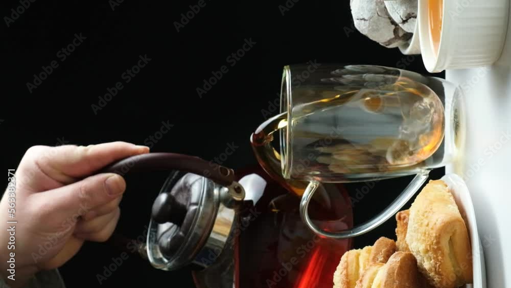 Black tea from the kettle is poured into a glass cup with a double bottom. Tea ceremony. Black tea from the kettle is poured into a glass cup with a double bottom. Tea ceremony.