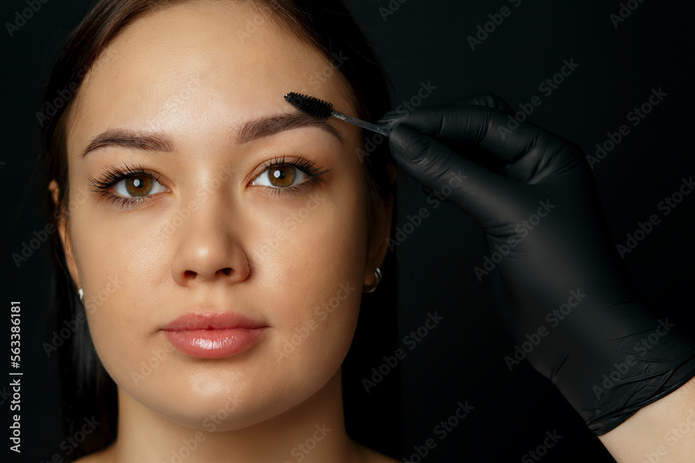 Beauty master brushing client's eyebrows after permanent makeup