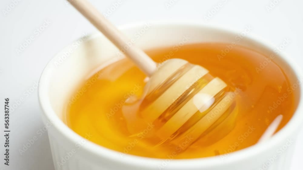 Liquid bee honey in a wooden spoon, showing linden fresh honey on a white background. Liquid bee honey in a wooden spoon, showing linden fresh honey on a white background.