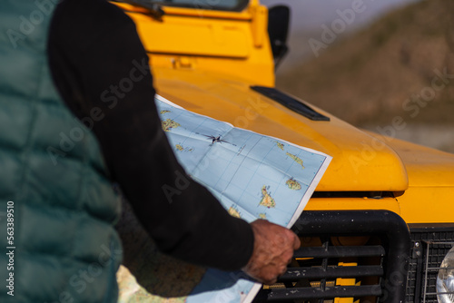 Wallpaper Mural senior man in green vest, looking at a map on top of yellow 4x4 car, outside image, horizontal image, copy space,concept of adventure, experiences. Torontodigital.ca
