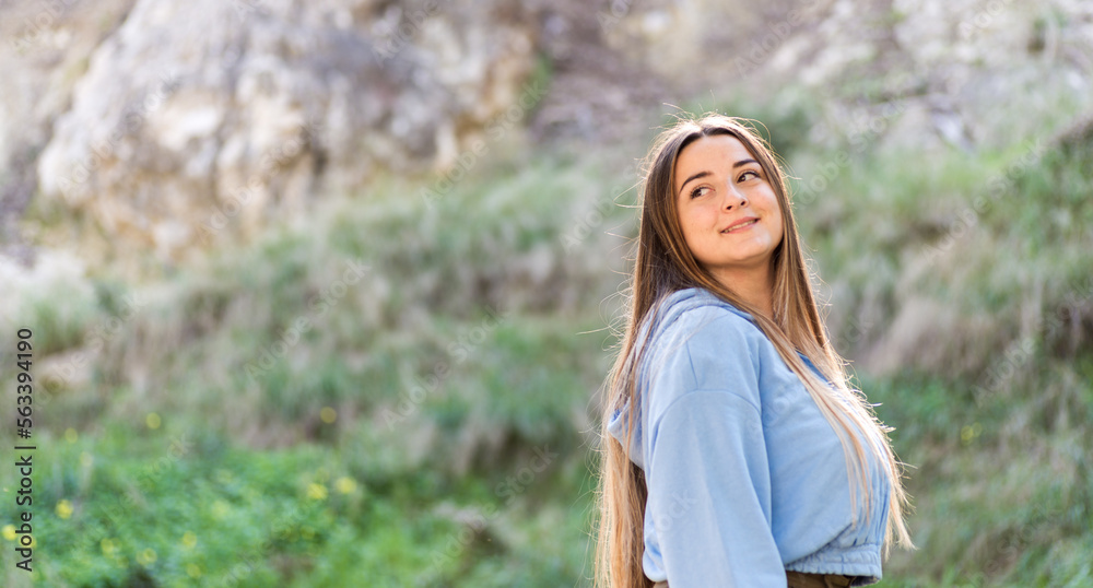 portrait of beautiful pensive woman, side image, blue t-shirt and green background, long brown hair, exterior image, horizontal with space copy, emotions portrait of beautiful pensive woman, side image, blue t-shirt and green background, long brown hair, exterior image, horizontal with space copy, emotions