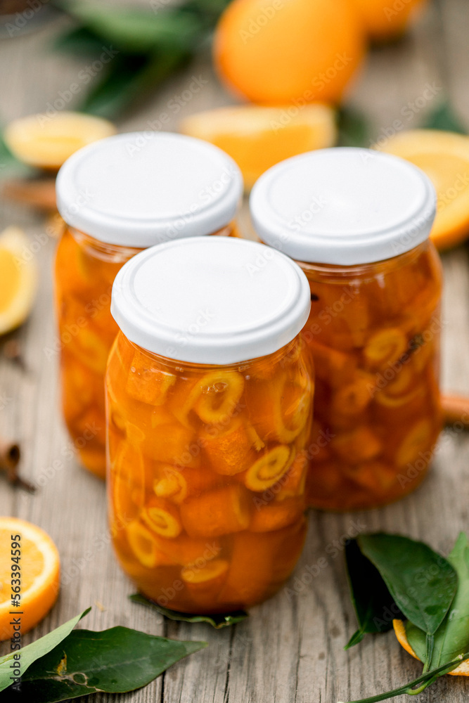 Homemade candied peels orange syrup in glass jar , on the background of sliced oranges Homemade candied peels orange syrup in glass jar , on the background of sliced oranges