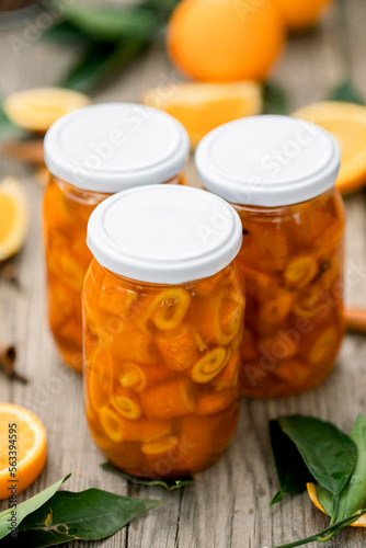 Homemade candied peels orange syrup in glass jar , on the background of sliced oranges