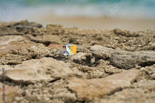 Geschliffenes, bunt schimmerndes Glas Quadrat auf Felsen am Strand