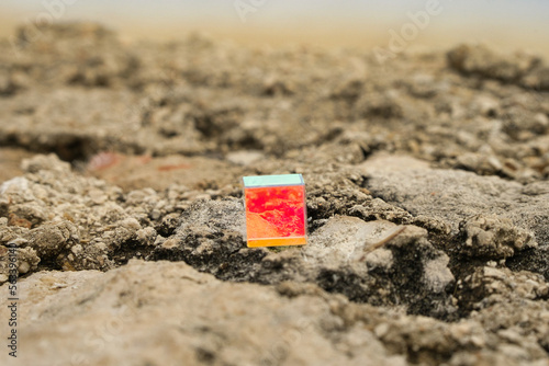 Geschliffenes, bunt schimmerndes Glas Quadrat auf Felsen am Strand