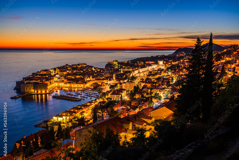 Dubrovnik, Croatia: Aerial panoramic view of the old town and old harbor on the shores of the Adriatic Sea during sunset; twilight view of small coastal town on the Croatian Mediterranean riviera