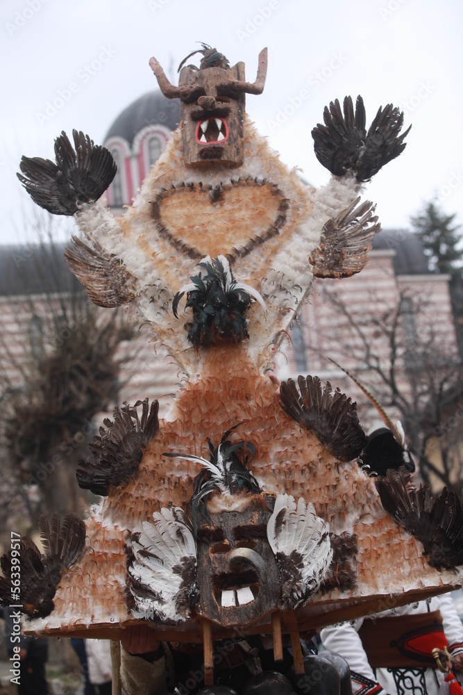 Breznik, Bulgaria - January 21, 2023: Unidentified people with traditional Kukeri costume are seen at the Festival of the Masquerade Games Surova in Breznik, Bulgaria