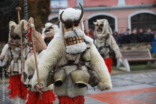 Breznik, Bulgaria - January 21, 2023: Unidentified people with traditional Kukeri costume are seen at the Festival of the Masquerade Games Surova in Breznik, Bulgaria