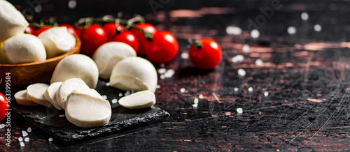 Sliced mozzarella on a stone board with tomatoes. 