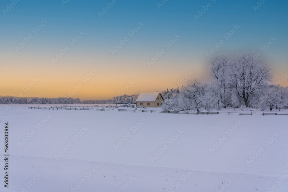 A house in the fields on a snowy winter morning, sunrise