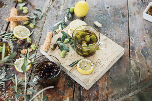 Various olives flavored with spices in cup and glass jar. Green olives, black olives. Front and top shot on wooden floor