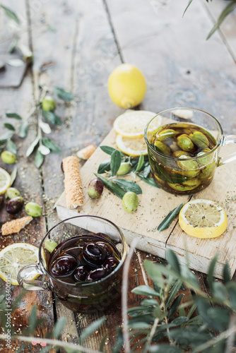 Various olives flavored with spices in cup and glass jar. Green olives, black olives. Front and top shot on wooden floor