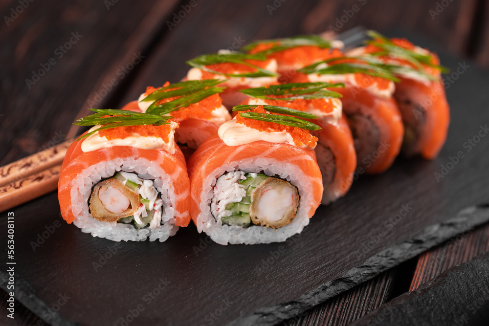 Sushi roll philadelphia with crab and cucumber and cream cheese, caviar on black background close-up. Sushi menu. Japanese food concept Sushi roll philadelphia with crab and cucumber and cream cheese, caviar on black background close-up. Sushi menu. Japanese food concept