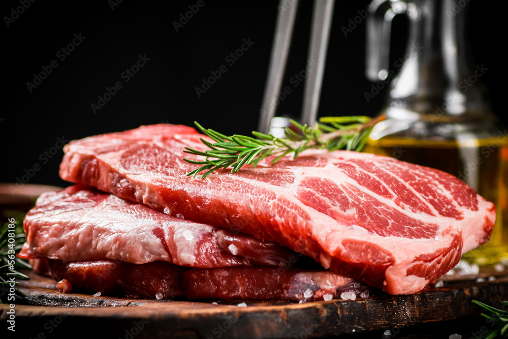 Raw pork steak on a cutting board with fork. 