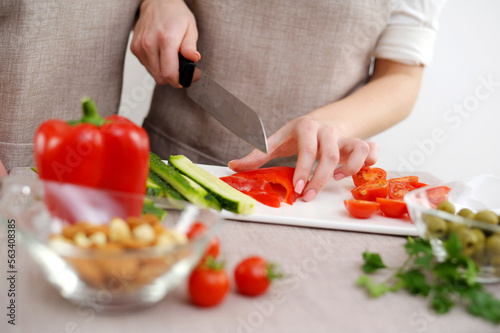 Close up cropped image of cutting board and couple cutting vegetables in the kitchen together, preparing food meal at home. Vegetarian healthy food Couple preparing a meal cut bell pepper