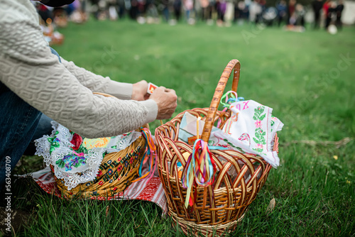 A man lights a candle on an Easter candle during an Easter Orthodox service outside. Easter basket with food for consecration with holy water. photo