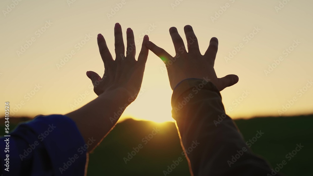 Concept of dream of child and parent. Happy family mom and son stretch their hands to sun and sky, prayer in nature. Hands of mom, daughter on background of sun, sunset flare. People travel outdoors