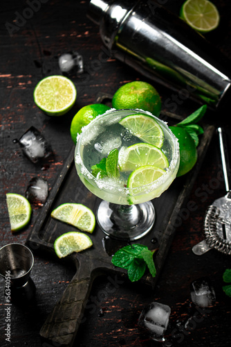 Margarita on a cutting board with pieces of lime and mint leaves. 