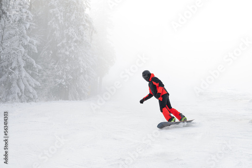 Freeride snowboarder running down the slope in mountains. Winter sport and recreation concept.