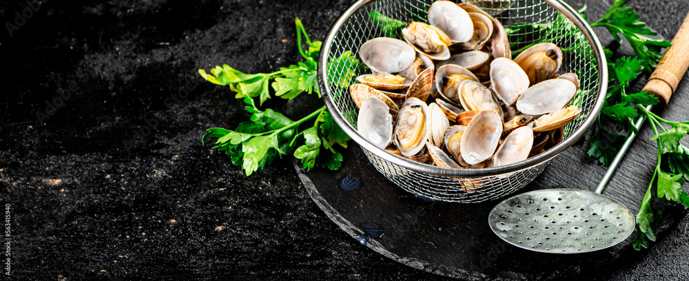 Fresh vongole in a colander on a stone board with parsley. 