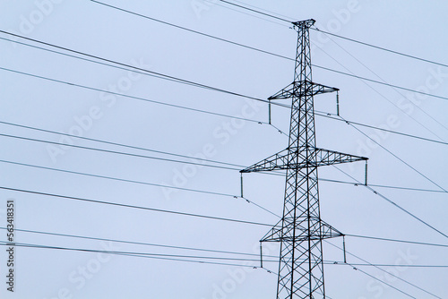 New large mast of an air power line close up, high voltage electricity pylon with thick wires and insulators, blue sky on background. Traditional energy. Electric power concept.