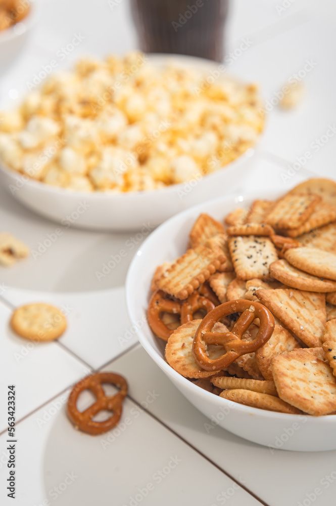 Homemade goodies, fast food - a bowl with popcorn, crackers and cookies on a white table. Homemade goodies, fast food - a bowl with popcorn, crackers and cookies on a white table.