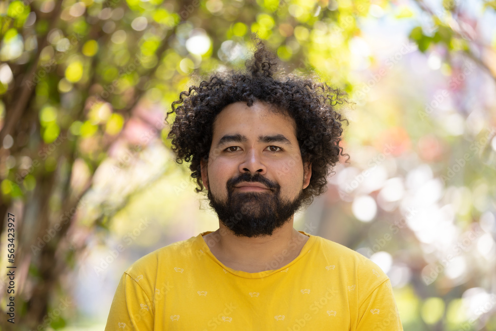 portrait of a Mexican man with curly hair and beard isolated on bokeh background portrait of a Mexican man with curly hair and beard isolated on bokeh background