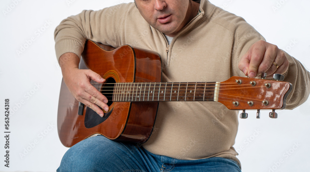 Obraz premium unrecognizable person tuning the guitar on a white background. studio photography
