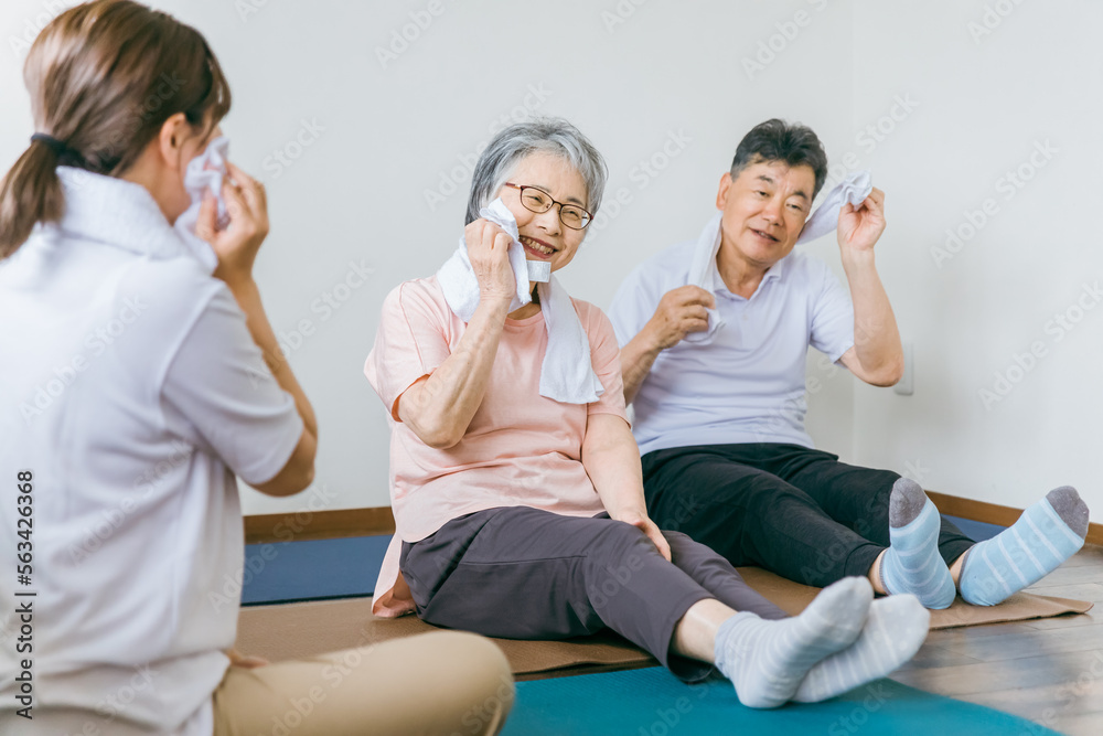 老人ホームでヨガ・体操・運動・リハビリするシニア・高齢者の男女と理学療法士・介護士・トレーナー