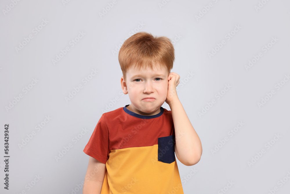 Little boy suffering from ear pain on light grey background Little boy suffering from ear pain on light grey background