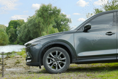 New black modern car on ground near river