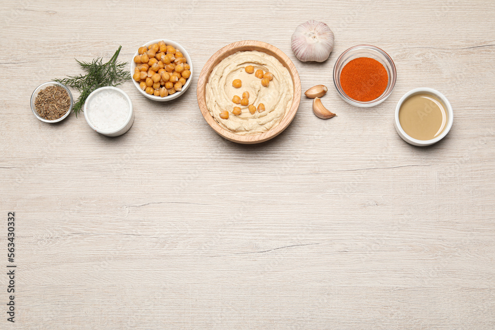 Bowl with delicious hummus and different ingredients on white wooden table, flat lay. Space for text Bowl with delicious hummus and different ingredients on white wooden table, flat lay. Space for text
