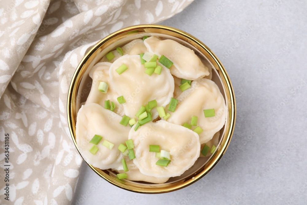 Cooked dumplings (varenyky) with tasty filling and green onion on light table, top view Cooked dumplings (varenyky) with tasty filling and green onion on light table, top view