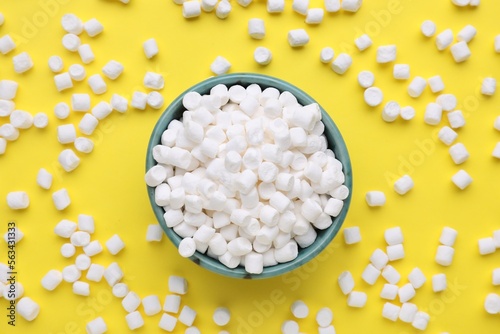 Bowl with delicious marshmallows on yellow background, flat lay