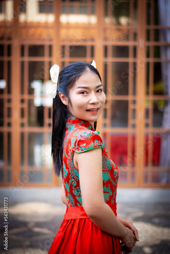 Asian woman in red traditional chiness dress sit at rest room,hand hold red envelope,oranges basket at side,feel happy and hope in happy chinese new year
