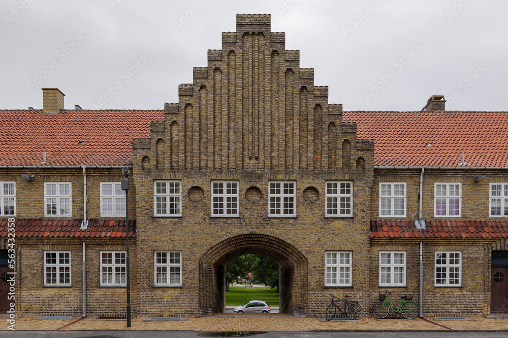 Fototapeta premium Exterior front elevation street view of typical old brick apartment with arch passage connect a road behind in Copenhagen, Denmark. 