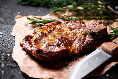 Grilled pork steak on paper with rosemary. 