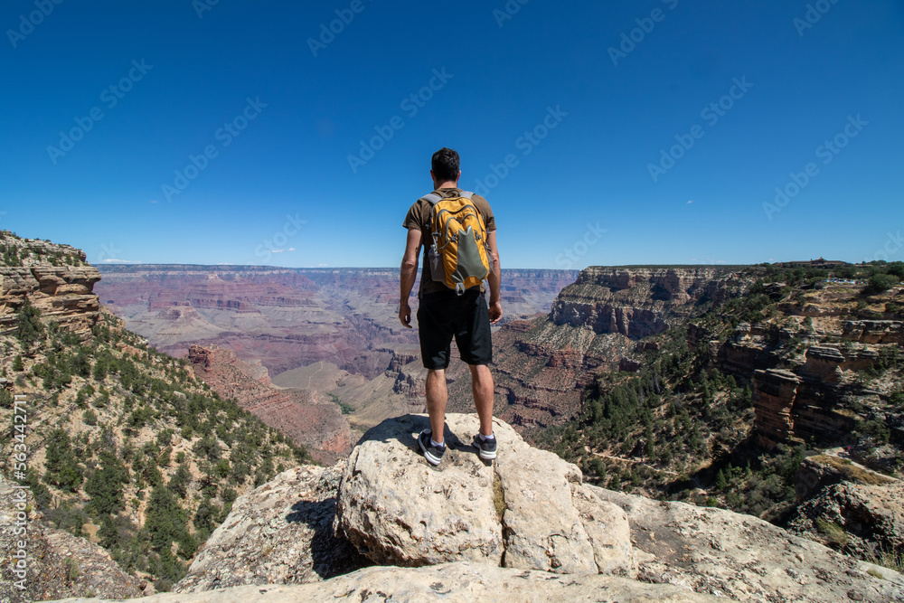 Fototapeta premium Man with yellow backpack at the edge of the Colorado canyon.