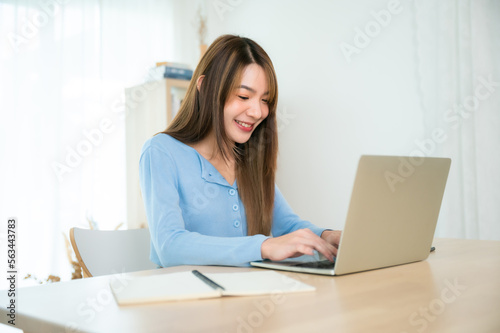 Young asian woman working at home. Female using computer laptop on desk at house