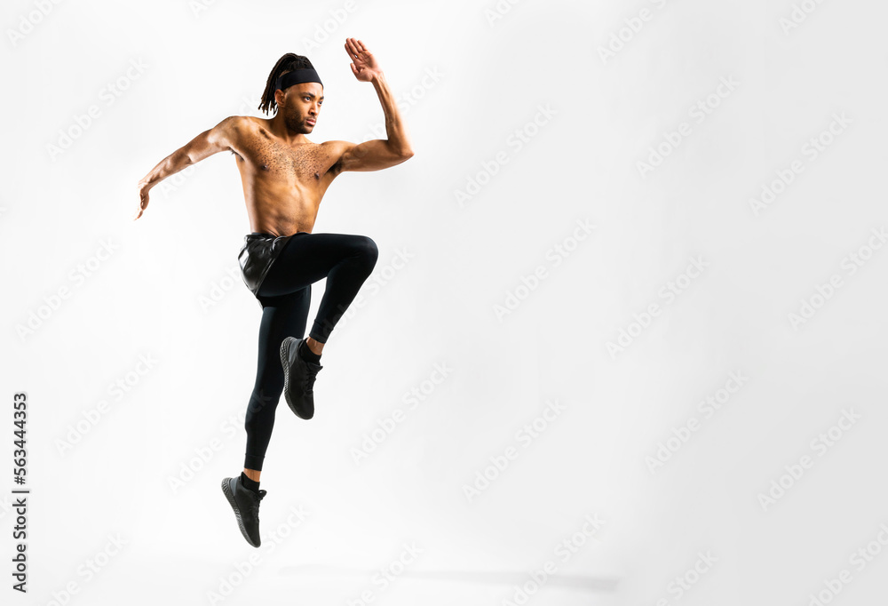 Obraz premium Young athletic Black man doing plyometric lunge jump exercise on white background in an indoor studio