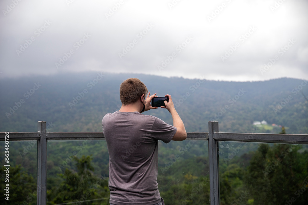 A man  taking photo of beautiful mountain landscape with mobile phone