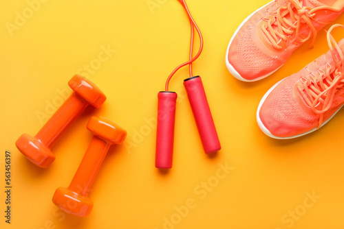 Skipping rope, dumbbells and sneakers on yellow background © Pixel-Shot