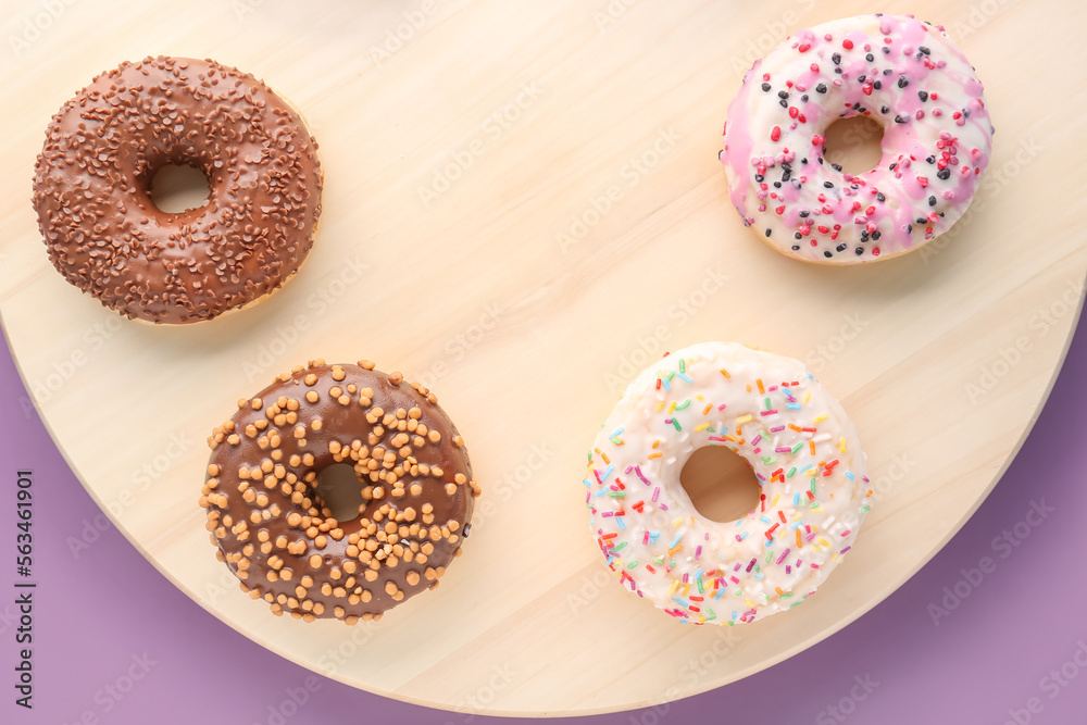 Wooden board with different sweet donuts on color background, closeup Wooden board with different sweet donuts on color background, closeup