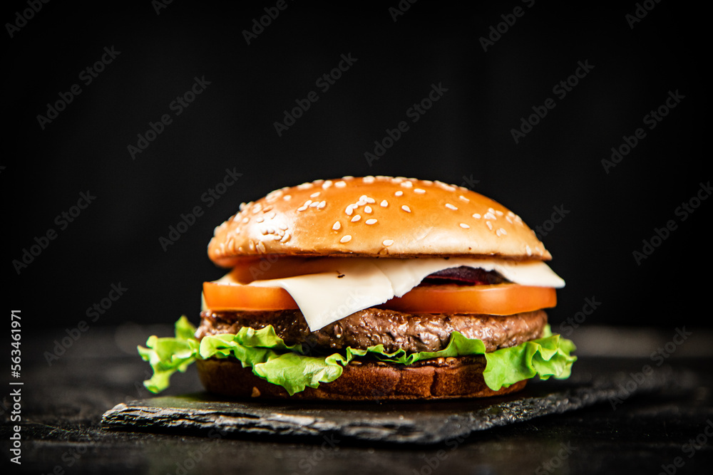 A burger on a stone board on a table. 