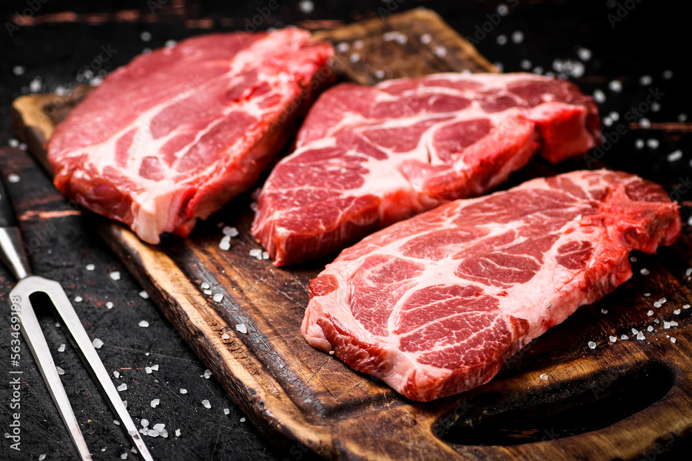 Raw pork steak on a wooden cutting board. 