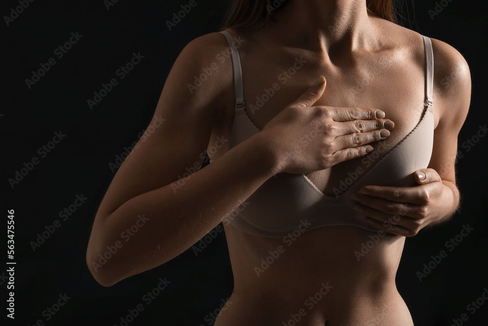 Naklejka premium Young woman in underwear on dark background, closeup. Breast cancer awareness concept